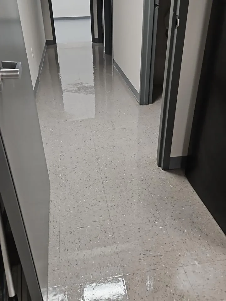 Bright commercial corridor with a reflective gray tile floor and light walls