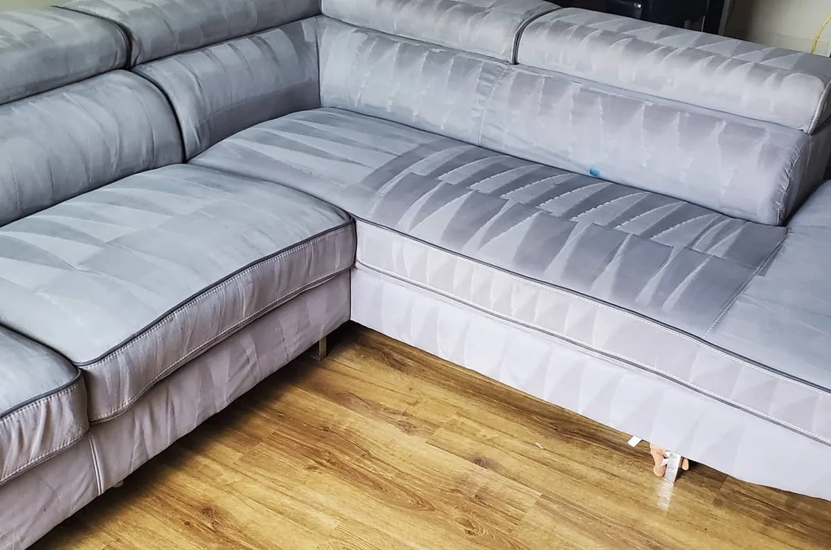 Gray fabric sectional sofa with visible upholstery cleaning lines beside a wood floor