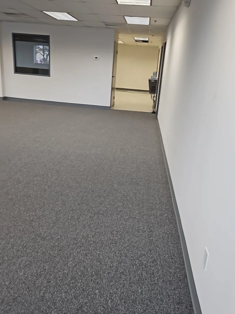 Gray carpet extending through an empty commercial room and corridor