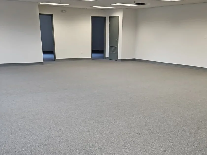 Open commercial room with gray carpet and light-colored walls