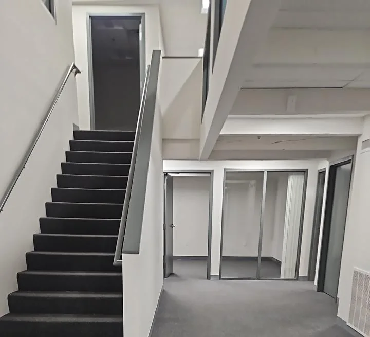 Carpeted staircase and common area with white walls and glass interior doors