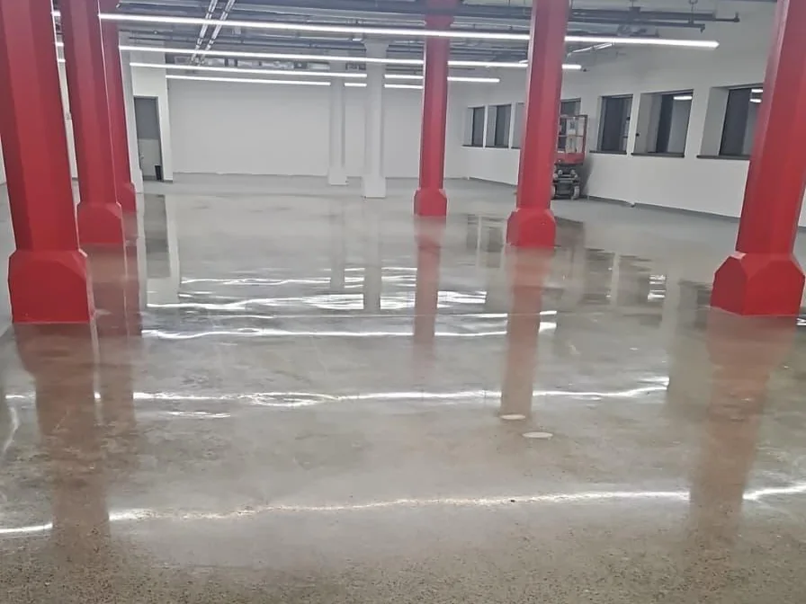 Polished commercial hall floor reflecting overhead lights and red columns
